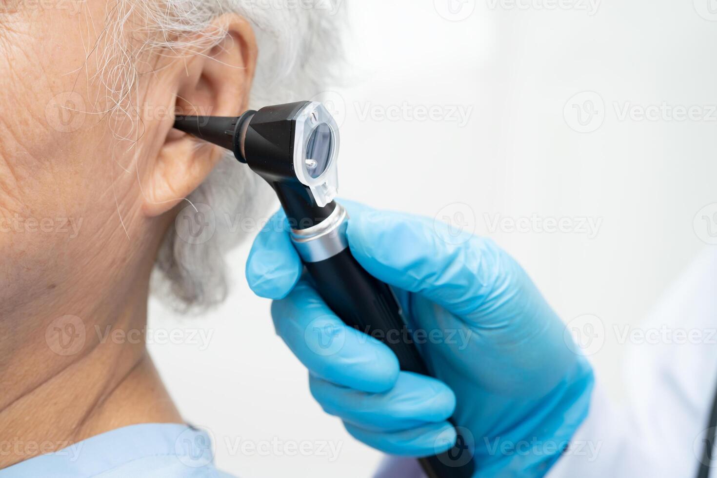 Otolaryngologist or ENT physician doctor examining senior patient ear otoscope photo