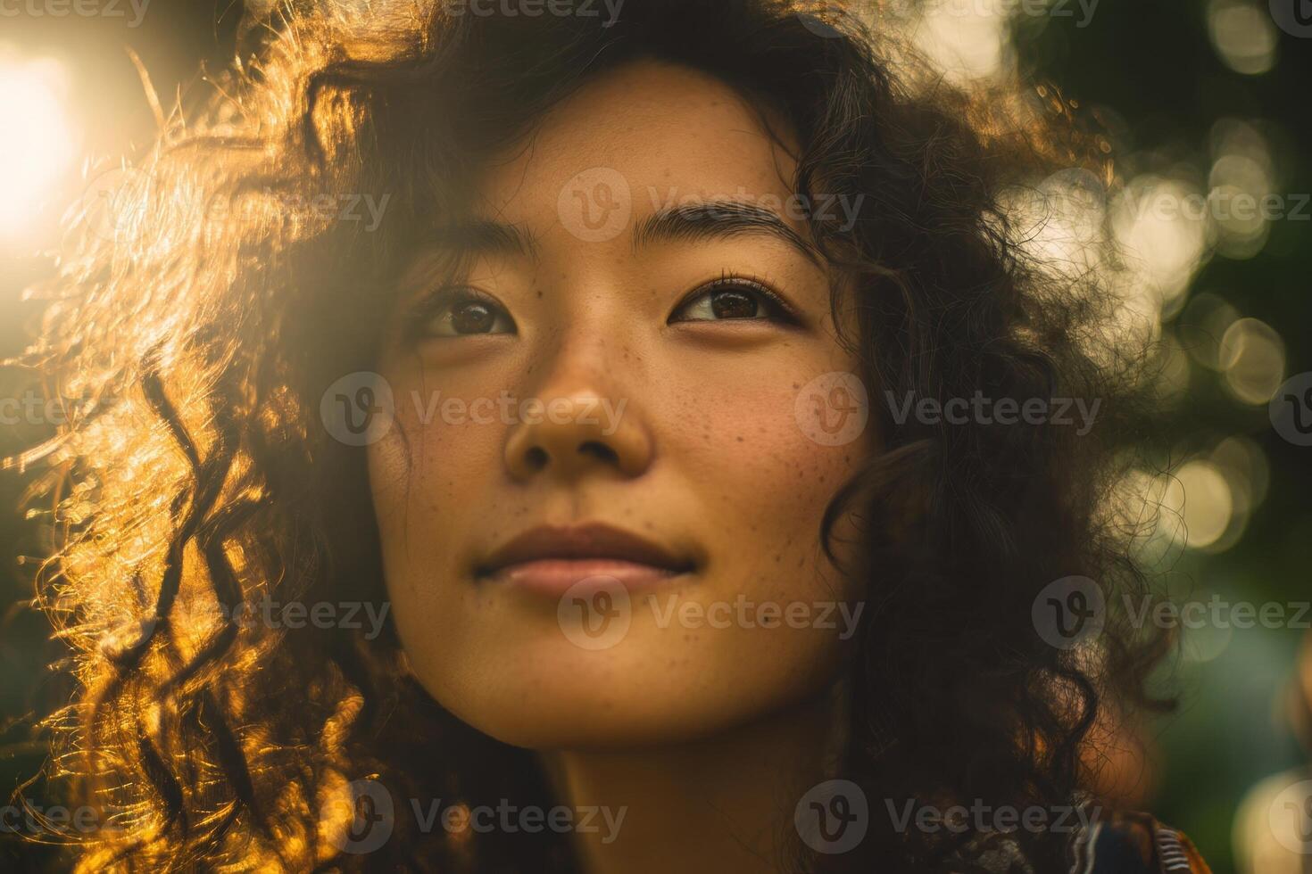 Young woman with curly hair and freckles gazes peacefully, sunlight softly illuminating her face, creating a warm and serene atmosphere with blurred natural elements in the background photo