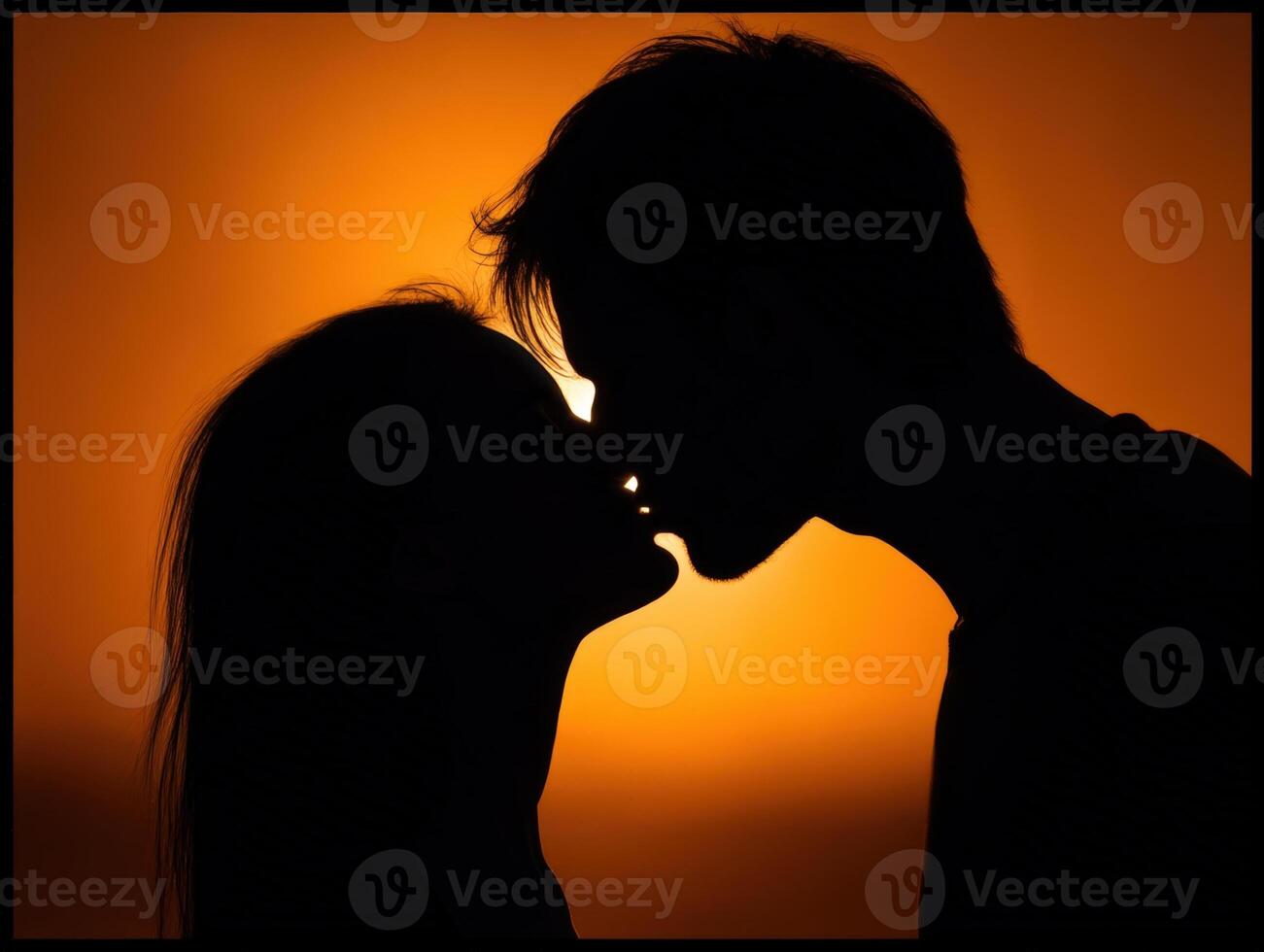 Silhouette of a couple kissing against a vibrant orange sunset. The soft glow outlines their profiles, creating a romantic and intimate atmosphere. No identifiable text present photo