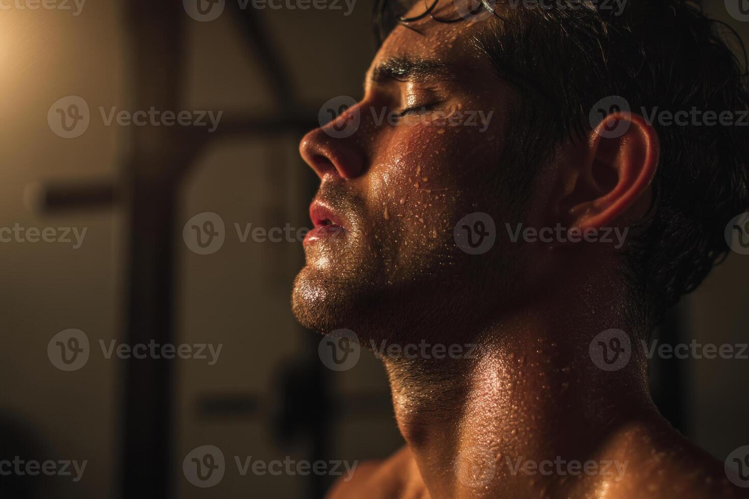 Sweaty, athletic man with closed eyes, illuminated by warm light, showing glistening skin and defined features. Focused expression, showcasing intensity and calmness post-exercise photo