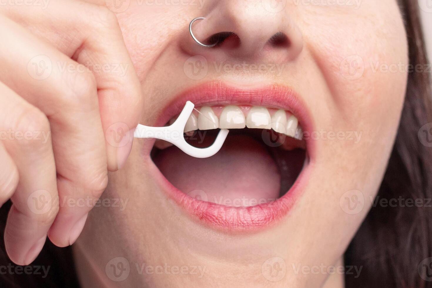 Woman uses dental floss on a stick, brushes her teeth. The concept of healthy teeth, self-care close up photo