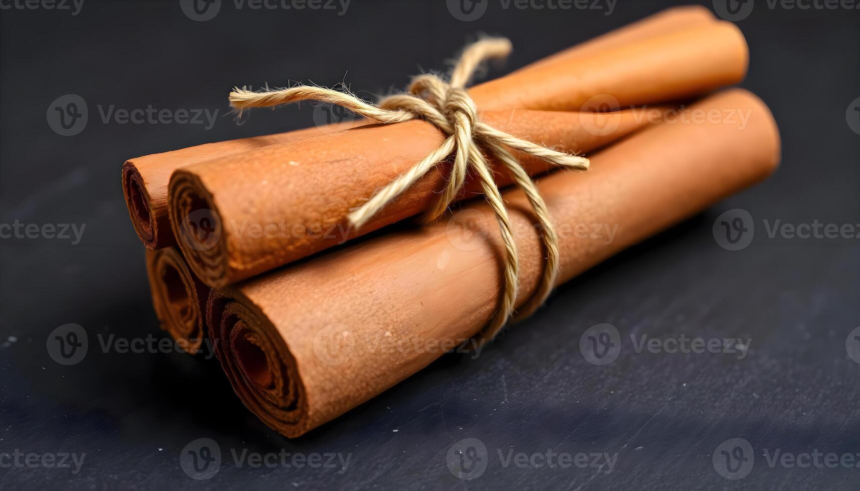 three rolled cinnamons tied with twine on a black surface photo