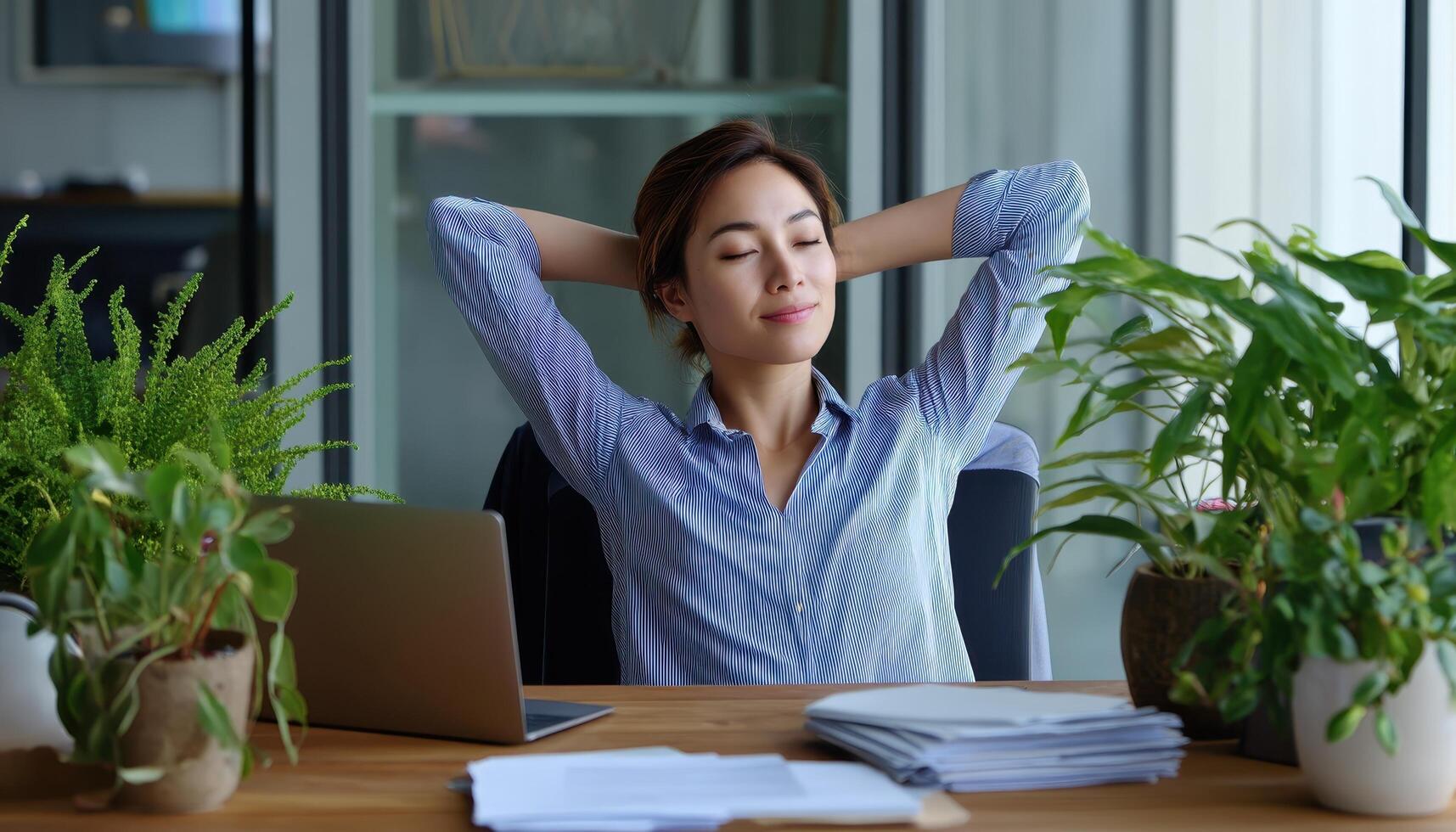Businesswoman taking a break to stretch in modern office with indoor plants photo