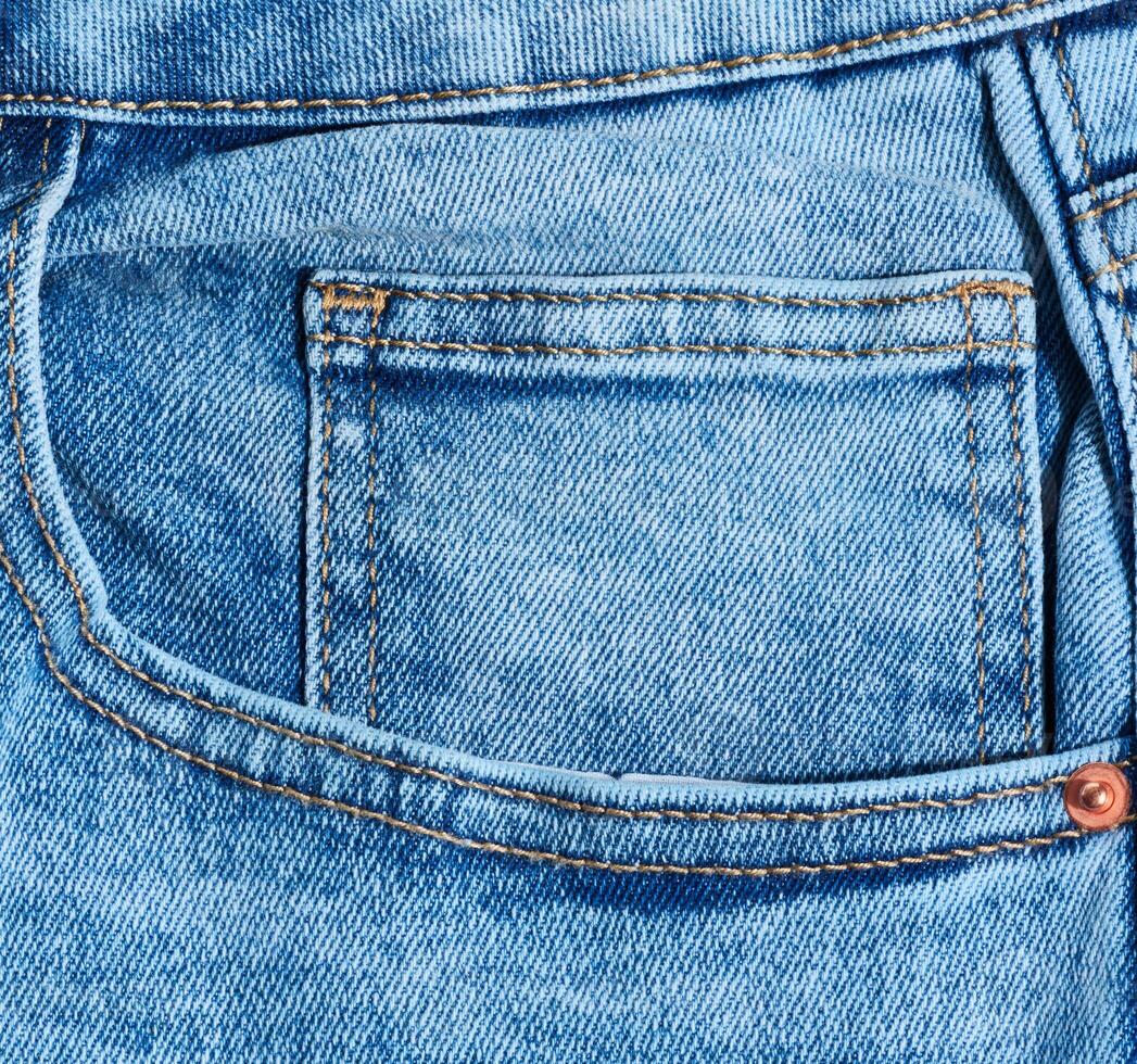 Close up of blue denim jeans showing a front pocket corner with distinct orange stitching detail photo