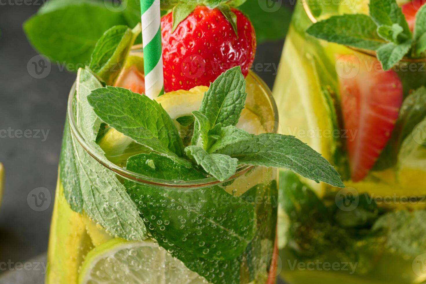 A refreshing drink in a glass with lemon slices, strawberries, fresh mint leaves, and sparkling water. Close up photo