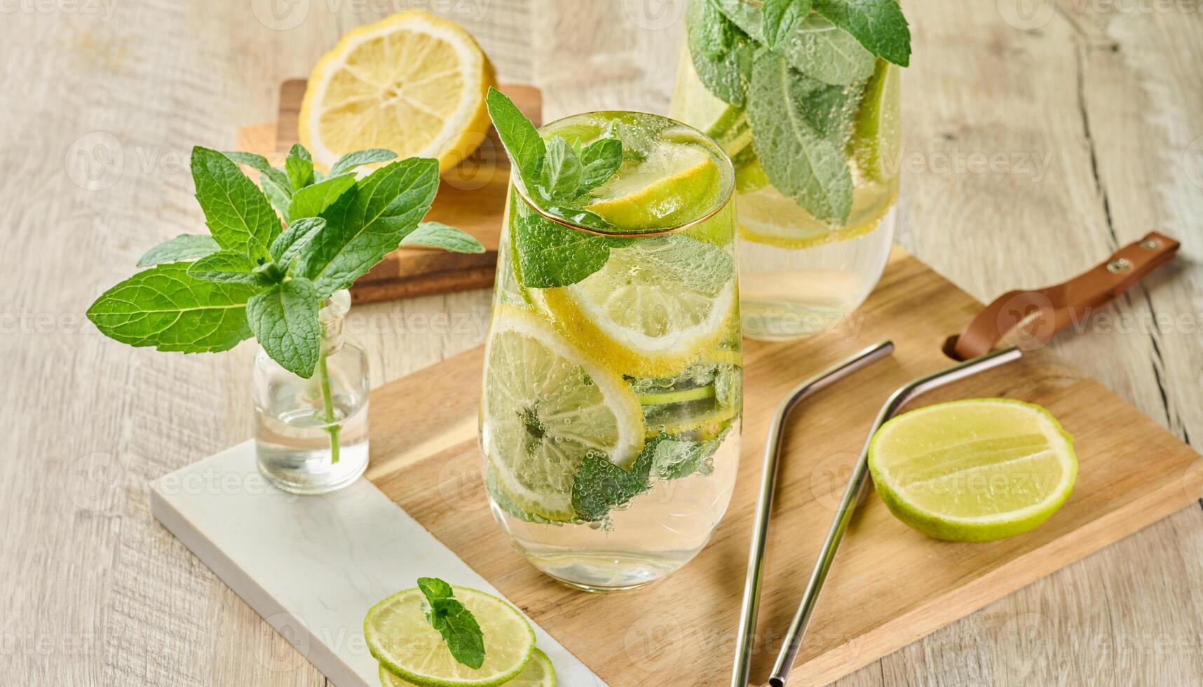 Refreshing citrus and mint drink in glasses with ice, lemon, lime, and mint leaves. Healthy summer beverage. photo