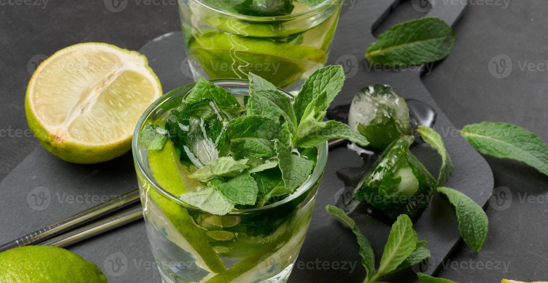 Refreshing mojito cocktail with lime, mint, strawberry, and ice on dark background, top view. photo