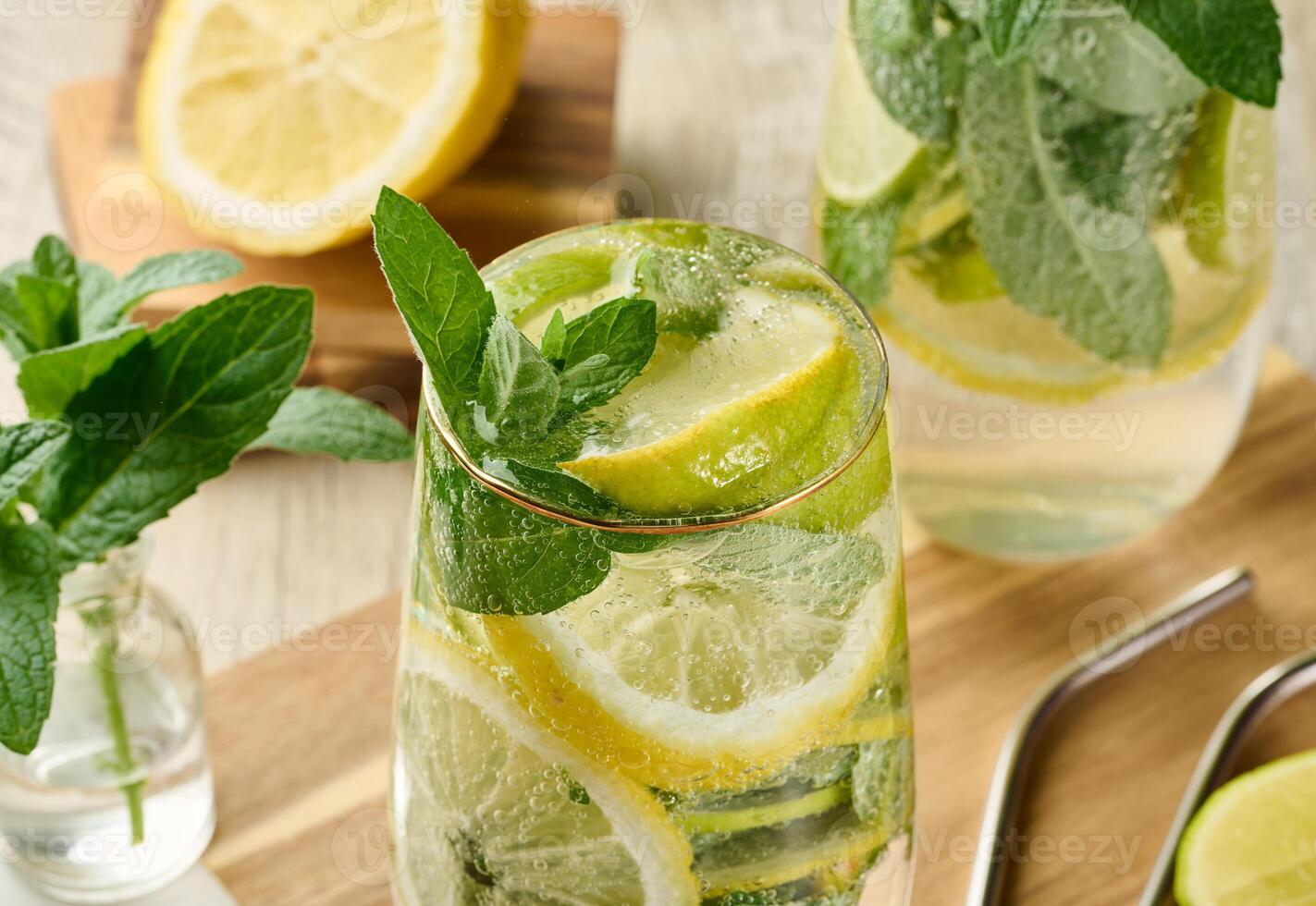 Refreshing citrus and mint drink in glasses with ice, lemon, lime, and mint leaves. photo