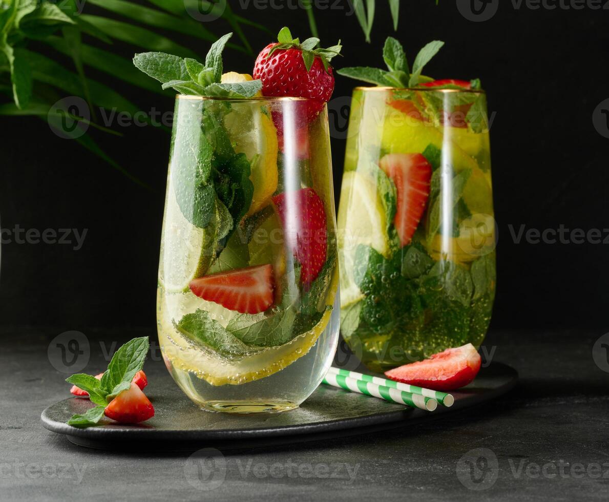 A refreshing drink in a glass with lemon slices, strawberries, fresh mint leaves, and sparkling water. photo