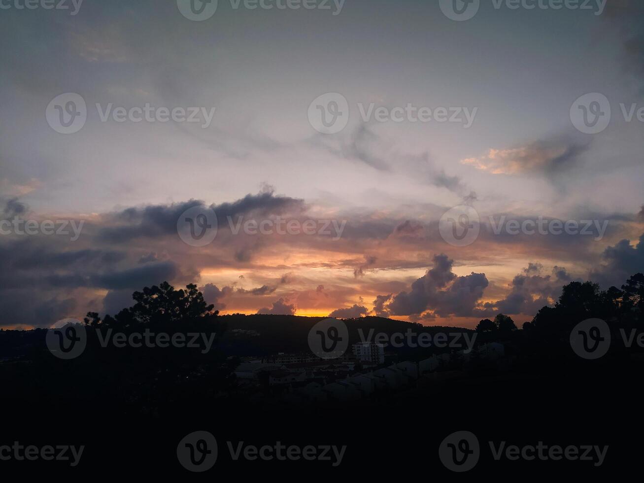 Serene sunset landscape with silhouetted trees and distant city lights. Peaceful, evocative image perfect for travel, nature, or tranquility themes. Ideal for websites, blogs, or print media. photo
