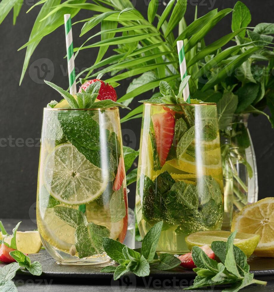 Refreshing drink in a glass with lemon slices, strawberries, fresh mint leaves, and sparkling water photo