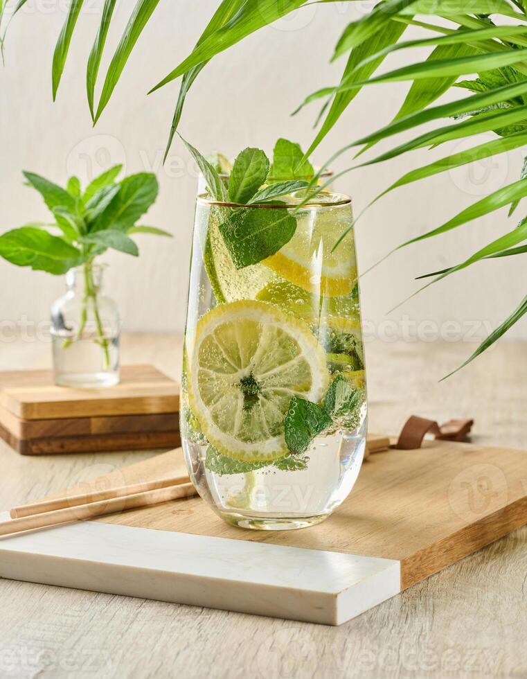 Refreshing citrus and mint drink in glasses with ice, lemon, lime, and mint leaves. Healthy summer beverage photo
