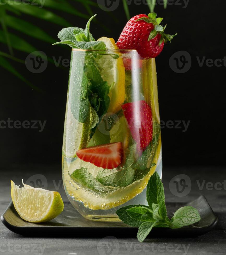 A refreshing drink in a glass with lemon slices, strawberries, fresh mint leaves, and sparkling water photo