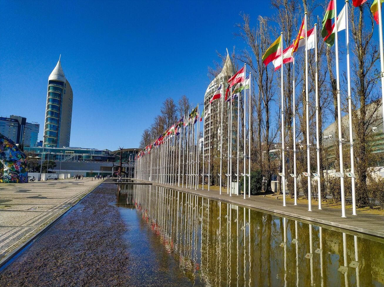LISBON, PORTUGAL - JANUARY 17, 2025 Modern architecture and international flags reflected in water. Global cooperation, travel, tourism. photo