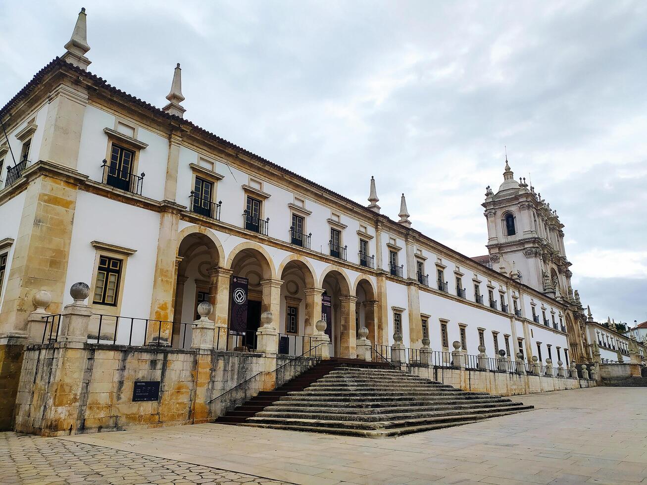 ALCOBACA, PORTUGAL - OCTOBER 15, 2024 Exterior of historic monastery, showcasing architecture, arches, and open square. Ideal for travel, history, or cultural publications. photo