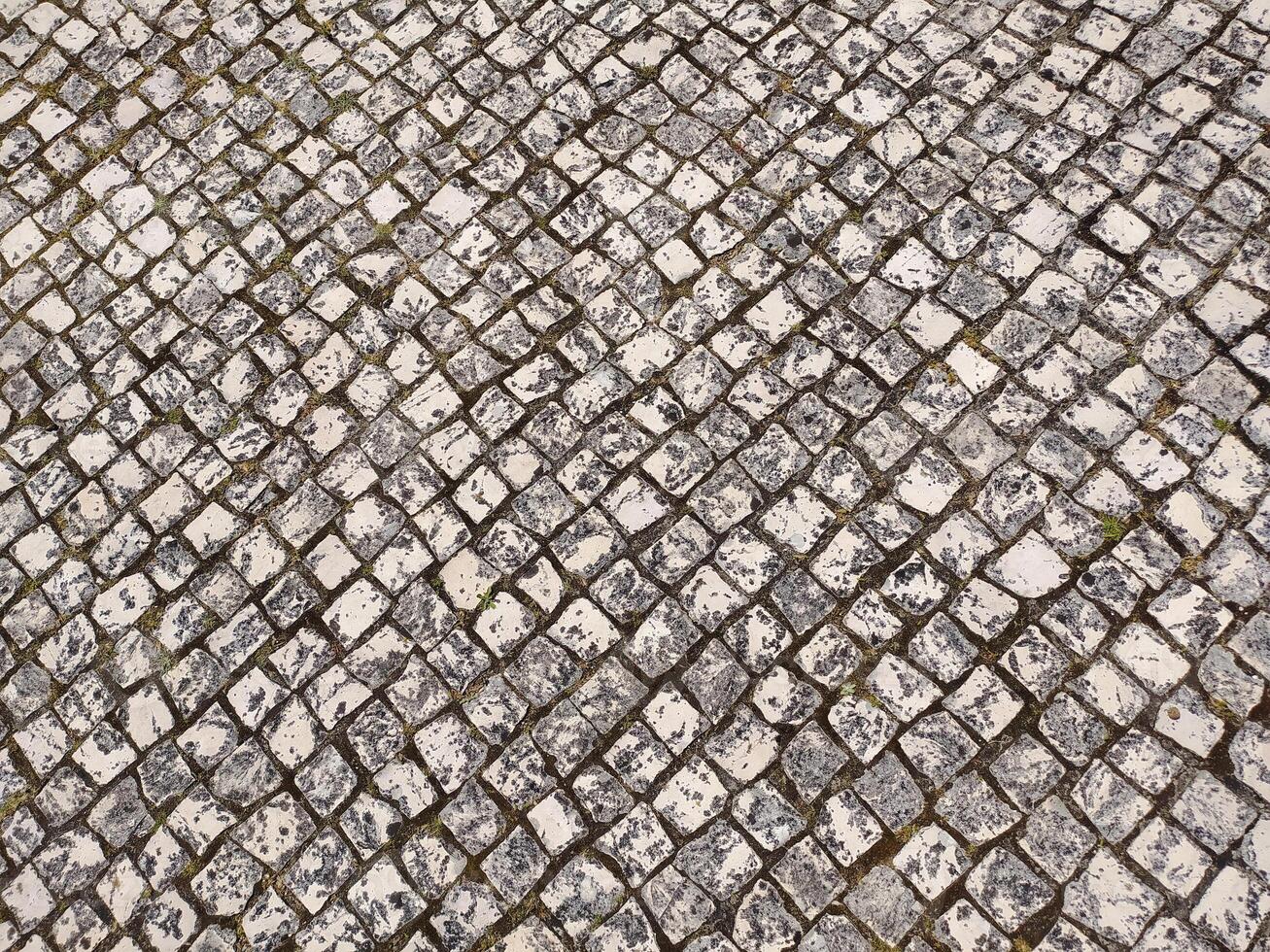 Highangle view of a weathered cobblestone pavement, showcasing a textured diamond pattern. photo