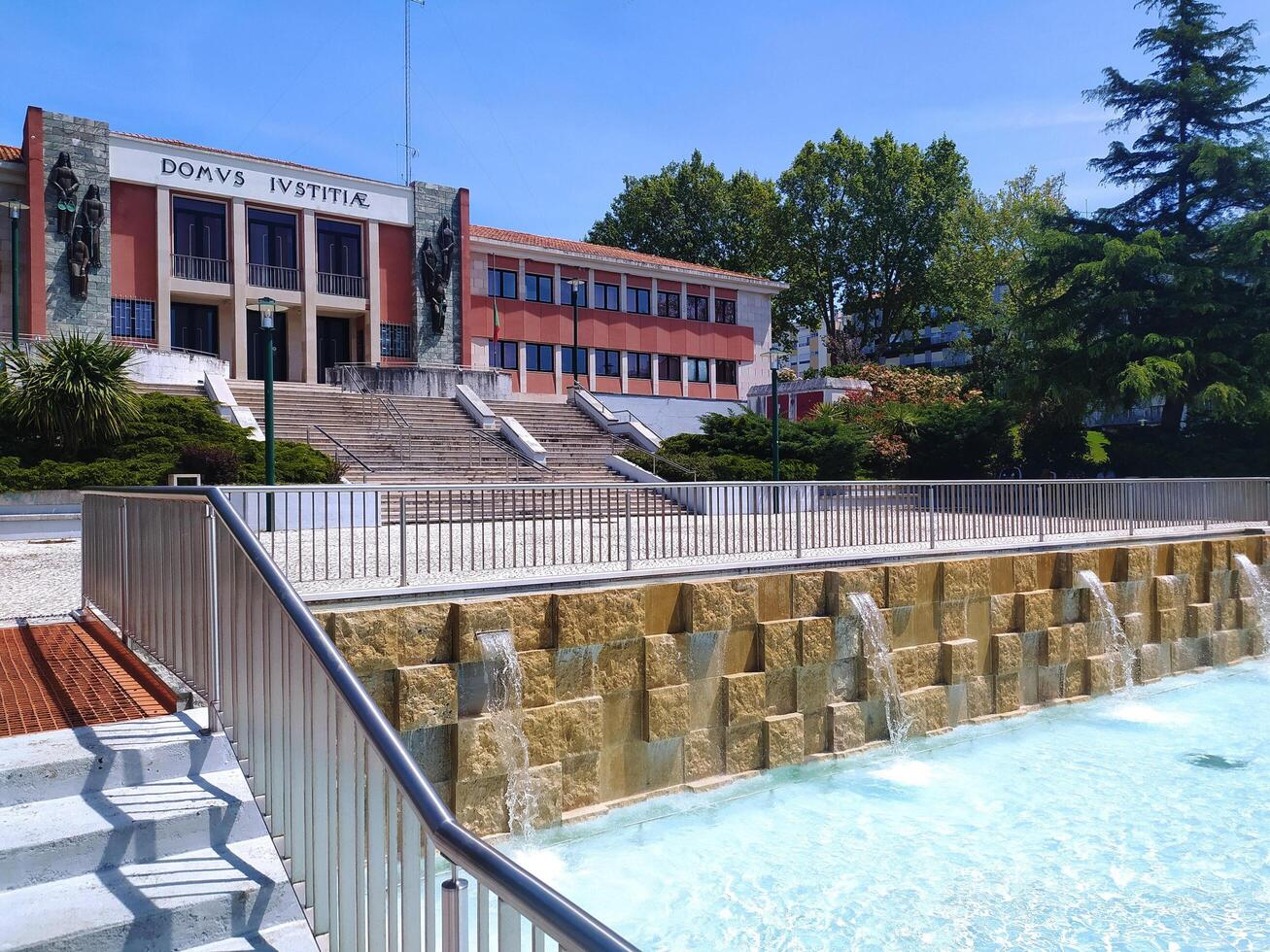 ALCOBACA, PORTUGAL - APRIL 27, 2025 Stone courthouse with a fountain, steps, and greenery. Sunny day. Architecture and landscape in a European town. photo