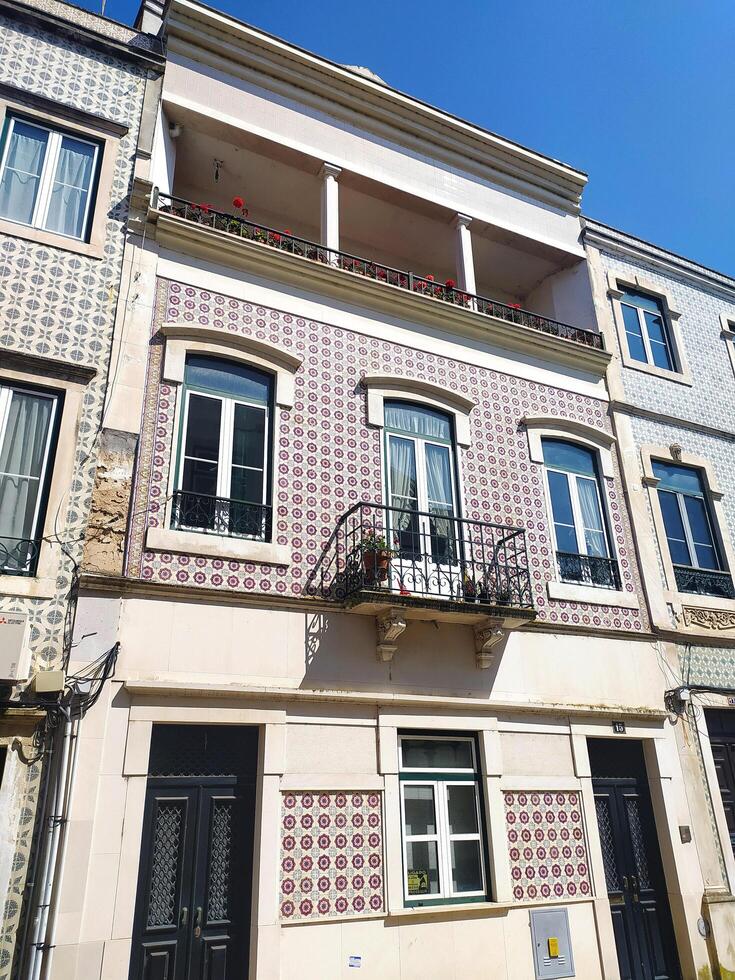 ALCOBACA, PORTUGAL - APRIL 24, 2025 Tiled building facade on a sunny day. Features balconies, windows, and architectural details. Represents history and culture. photo