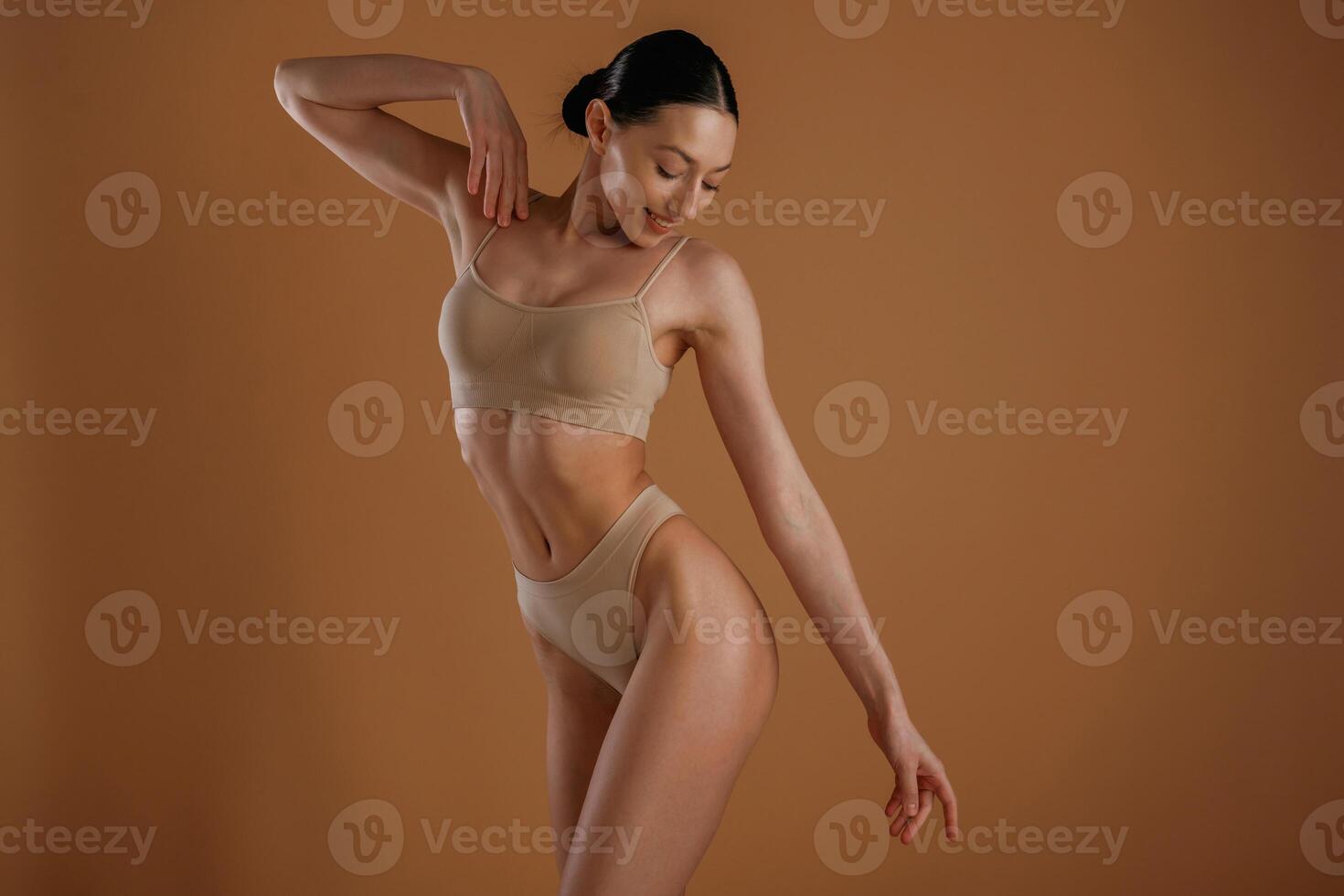 Creamy colored ,,underwear. Woman with slim body shape is posing against background photo