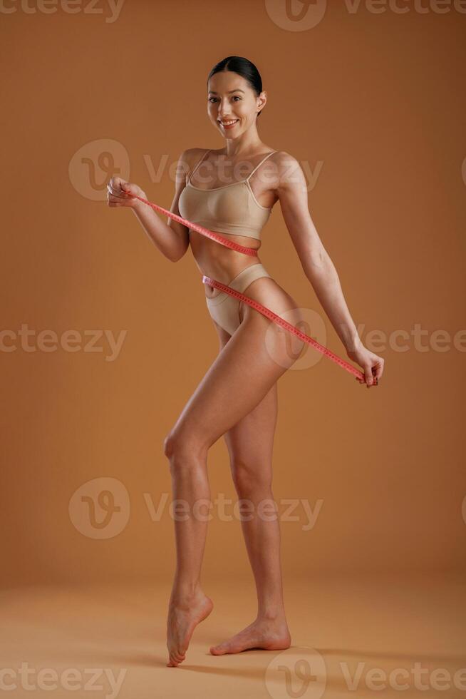 Red ,measuring tape, diet. Woman with slim body shape is posing against background photo