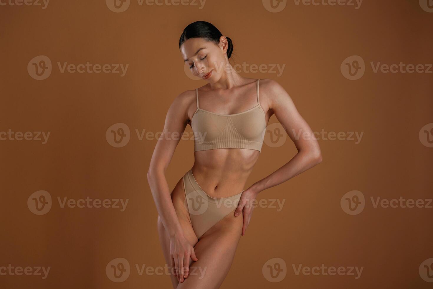 Creamy colored underwear. .Woman ,with slim body shape is posing against background photo