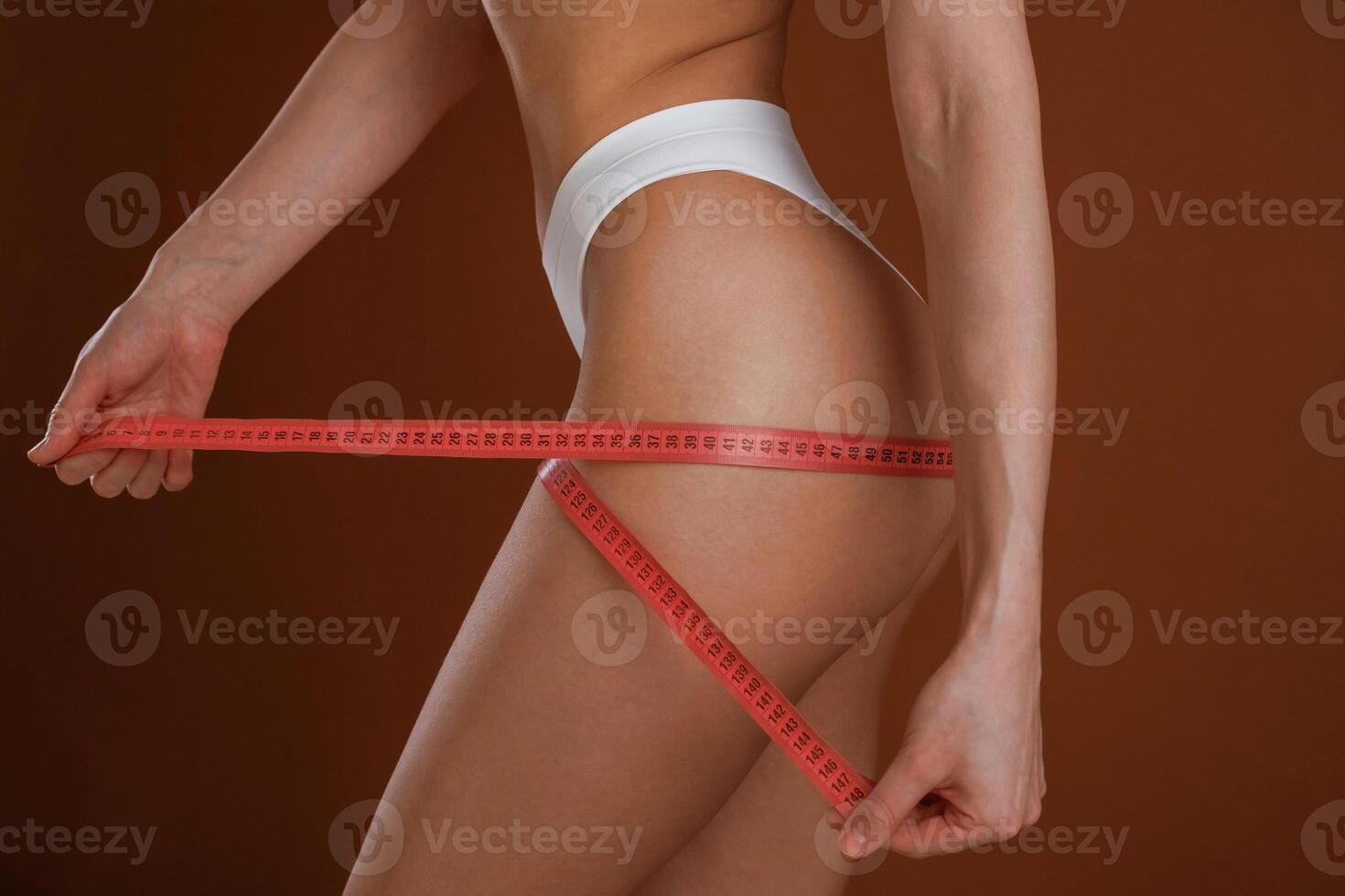 Measuring ,the leg, conception of weight,, loss. Woman with slim body shape is posing against background photo