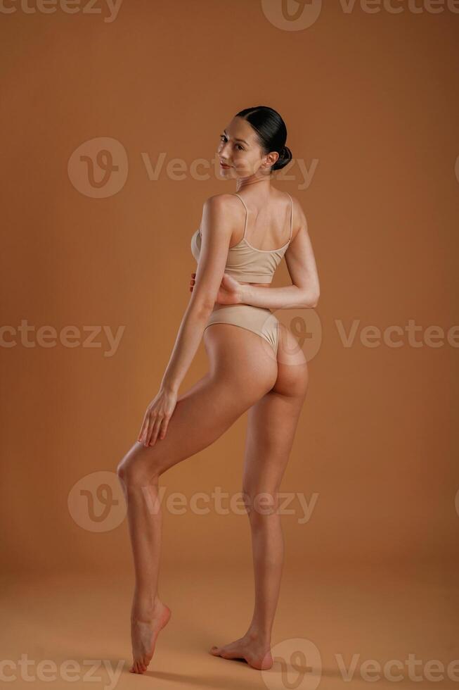 Back and ,side view. Woman with slim body shape is posing against background photo