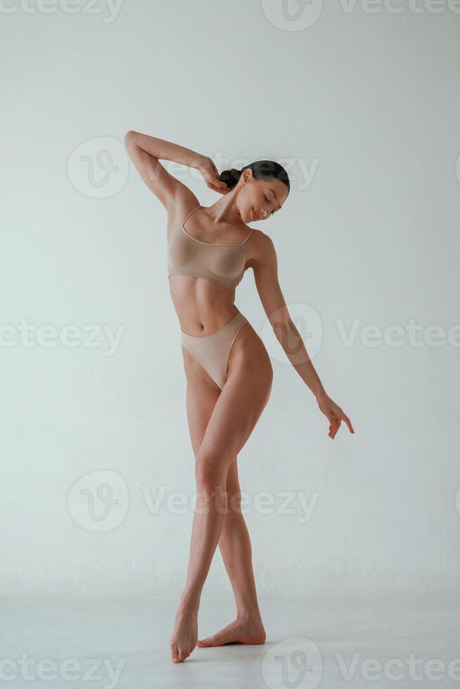 Woman with slim body shape is posing against background photo