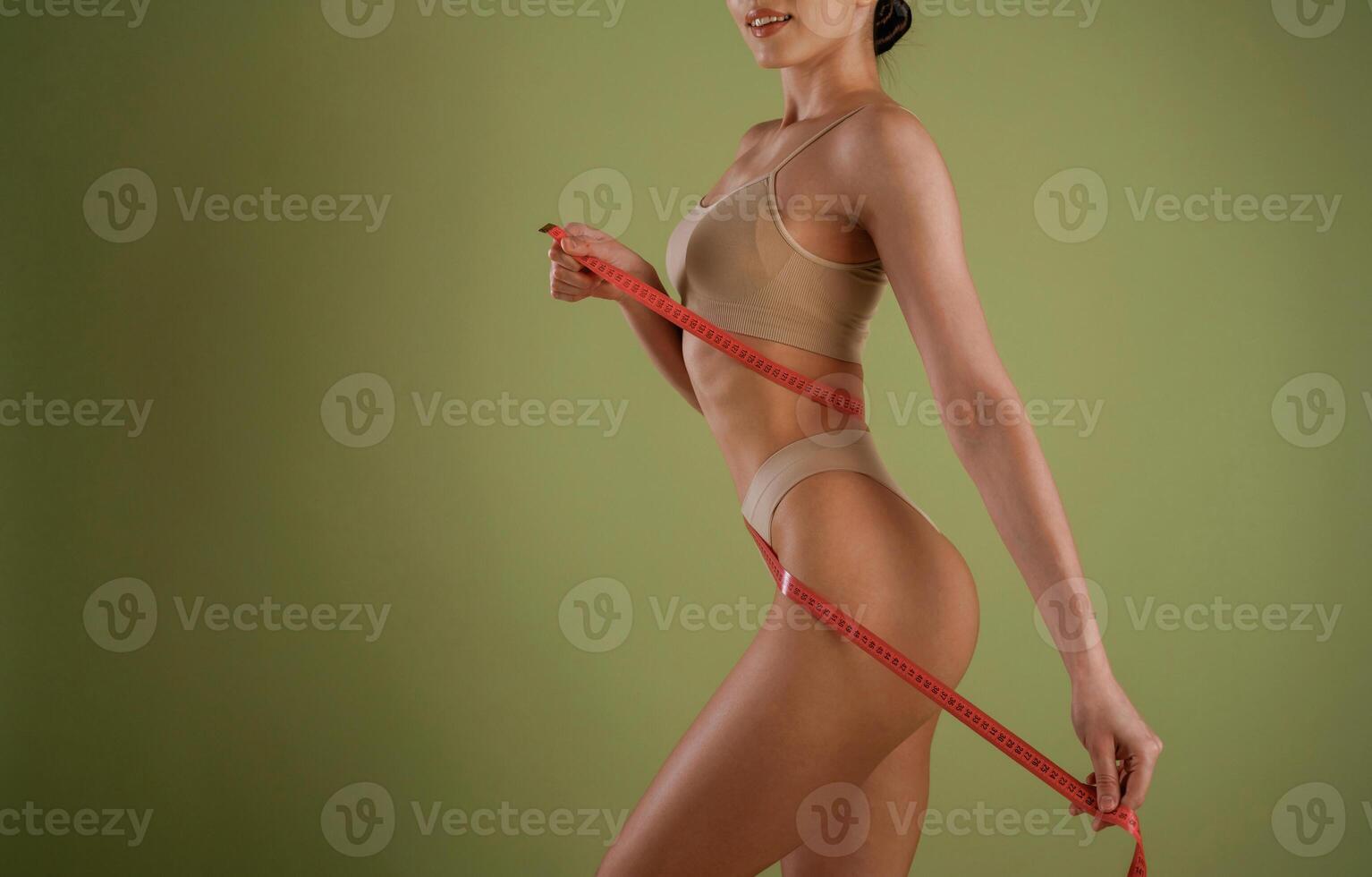 Results of diet, with, measuring tape. Woman with slim body shape is posing against background photo