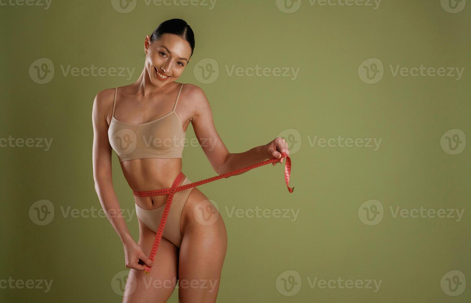 Results ,of diet, with measuring tape. Woman with slim body shape is posing against background photo