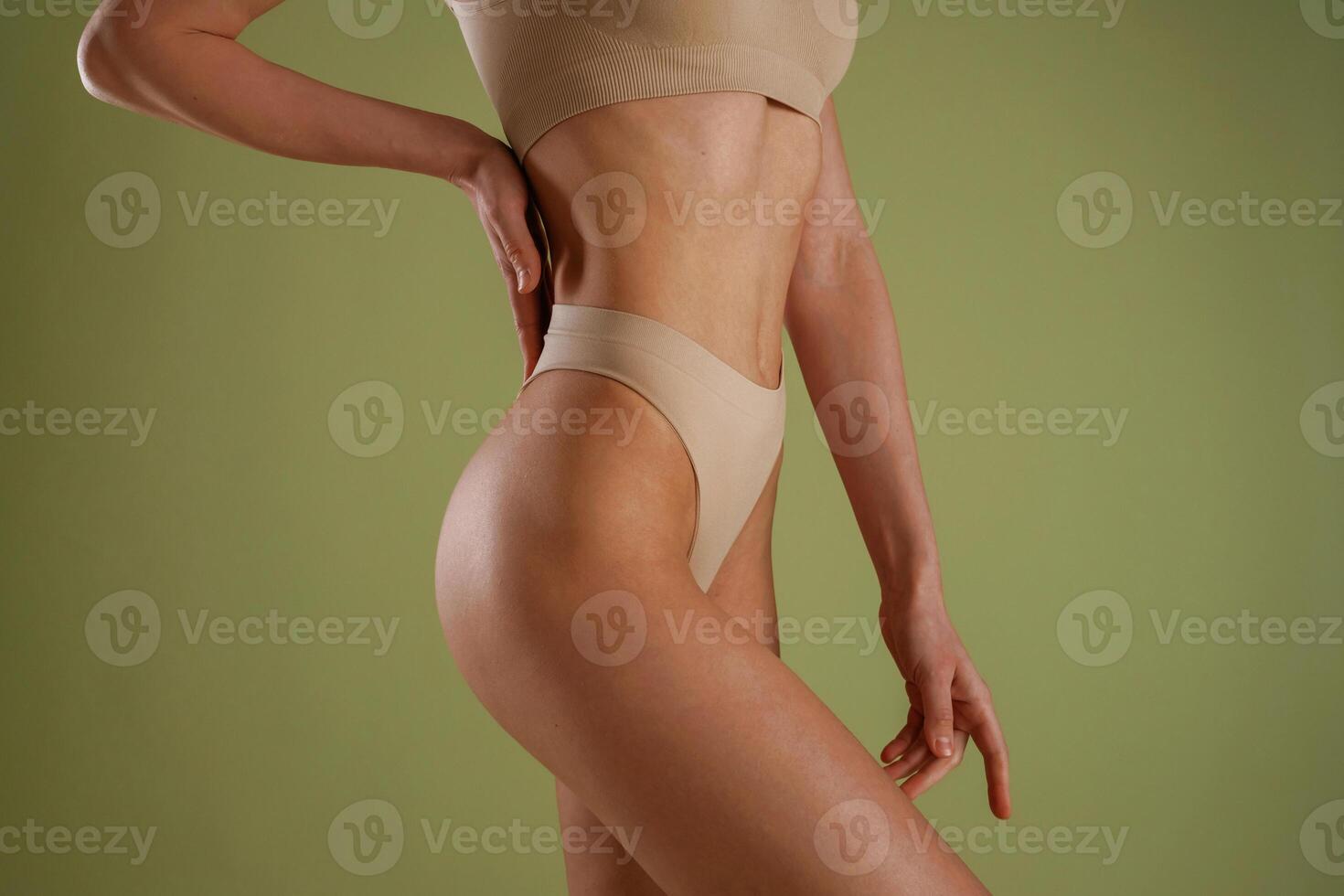 Side, close up view. Woman with slim body shape is posing against background photo