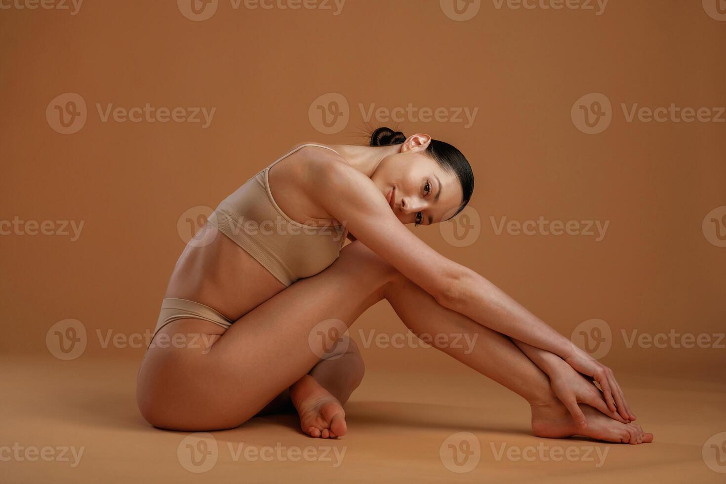 Sitting and resting ,,on the floor. Woman with slim body shape is posing against background photo