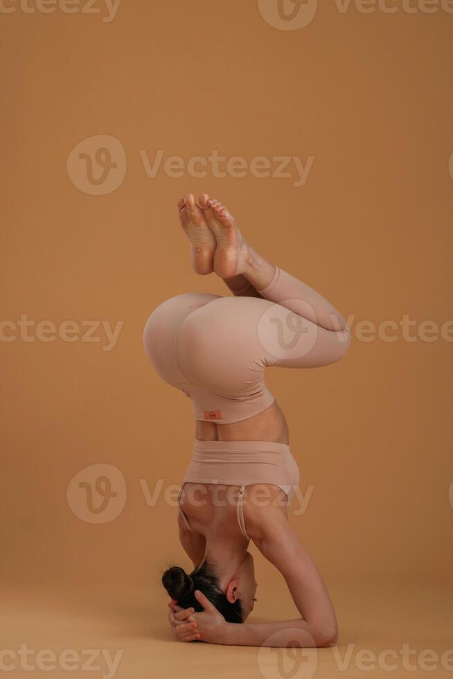 Doing headstand. Beautiful fitness woman is in the studio photo