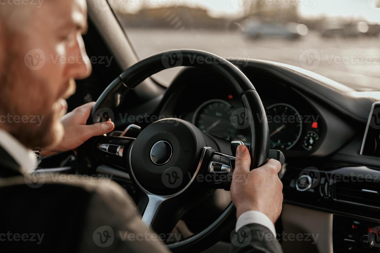 Close up, view ,of steering wheel. Man in black suit is sitting in the car, driving photo