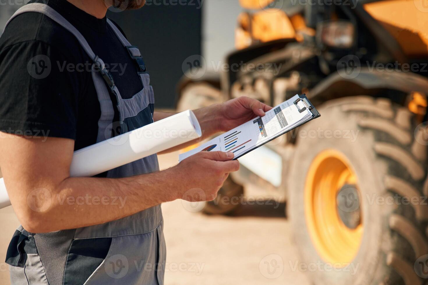 Data ,in the notepad,, reading. Man is with tractor. Agricultural worker photo