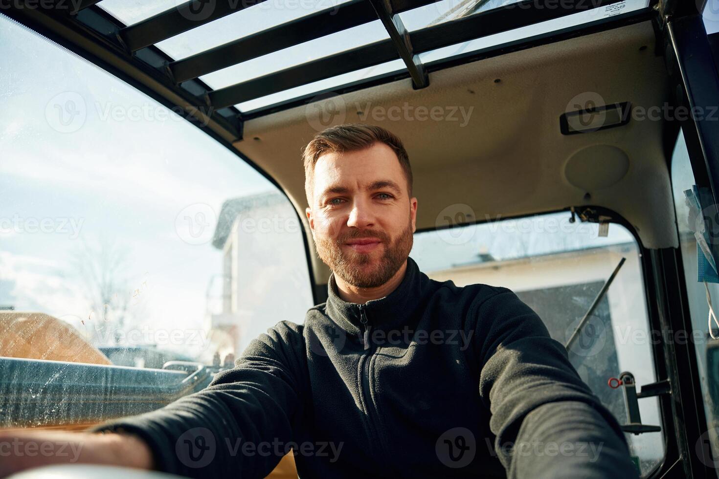 By, the steering wheel. Man is with tractor. Agricultural worker photo