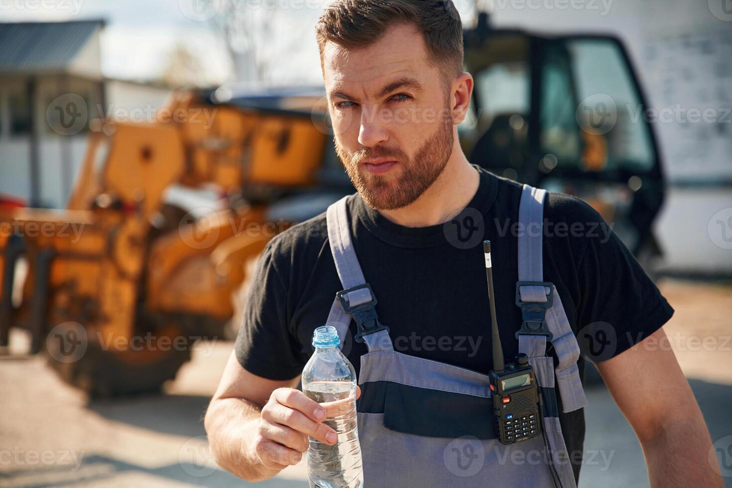 Drinking water, taking a break, tired.,.. Man is with tractor. Agricultural worker photo