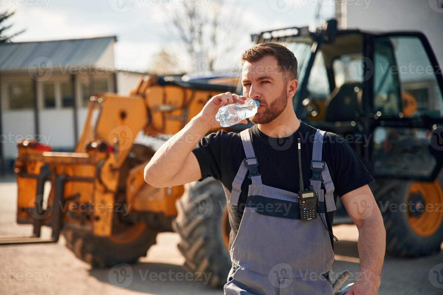 Drinking water, taking a break, tired.. Man is with tractor. Agricultural worker photo