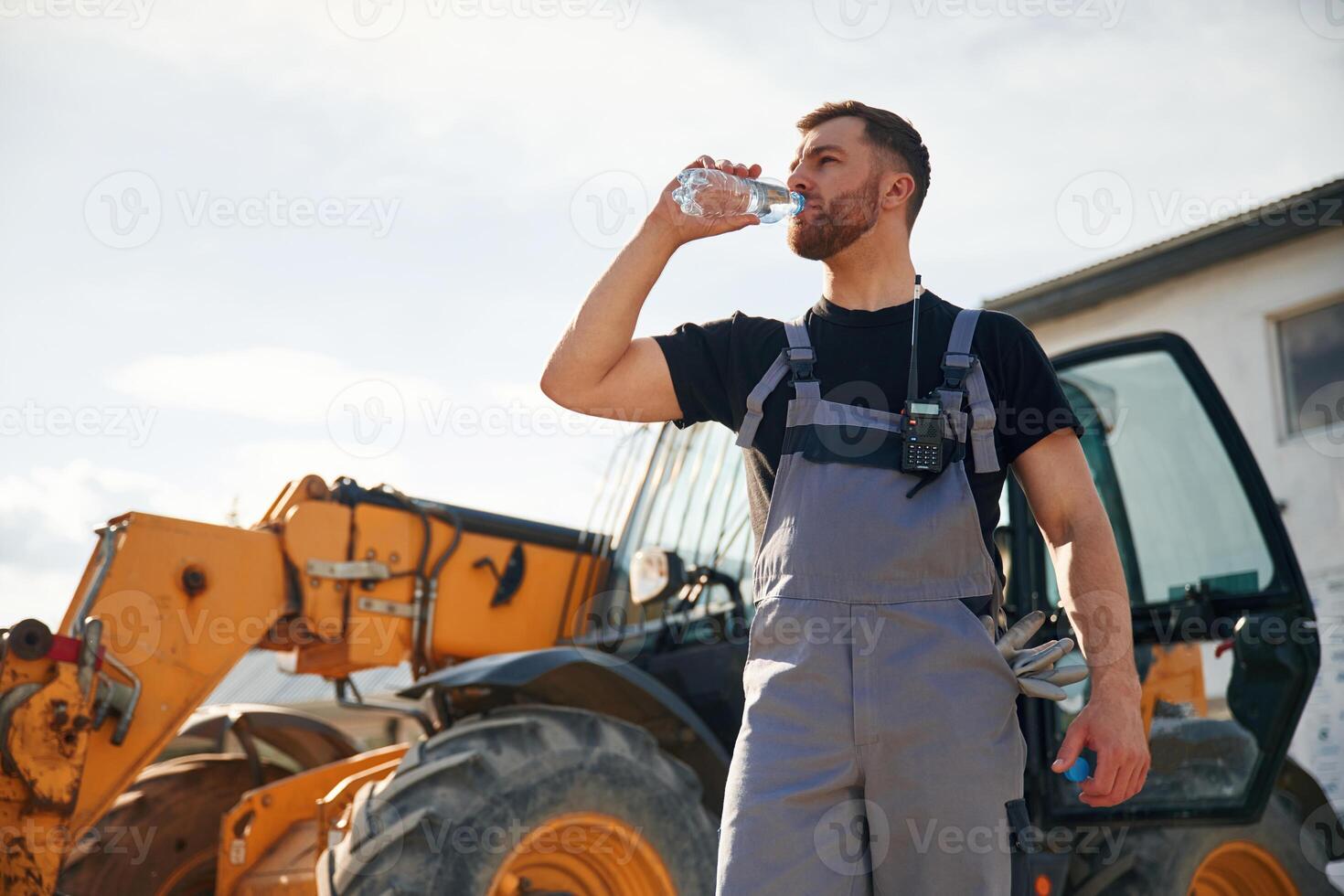 Drinking water, taking a break,, tired. Man is with tractor. Agricultural worker photo