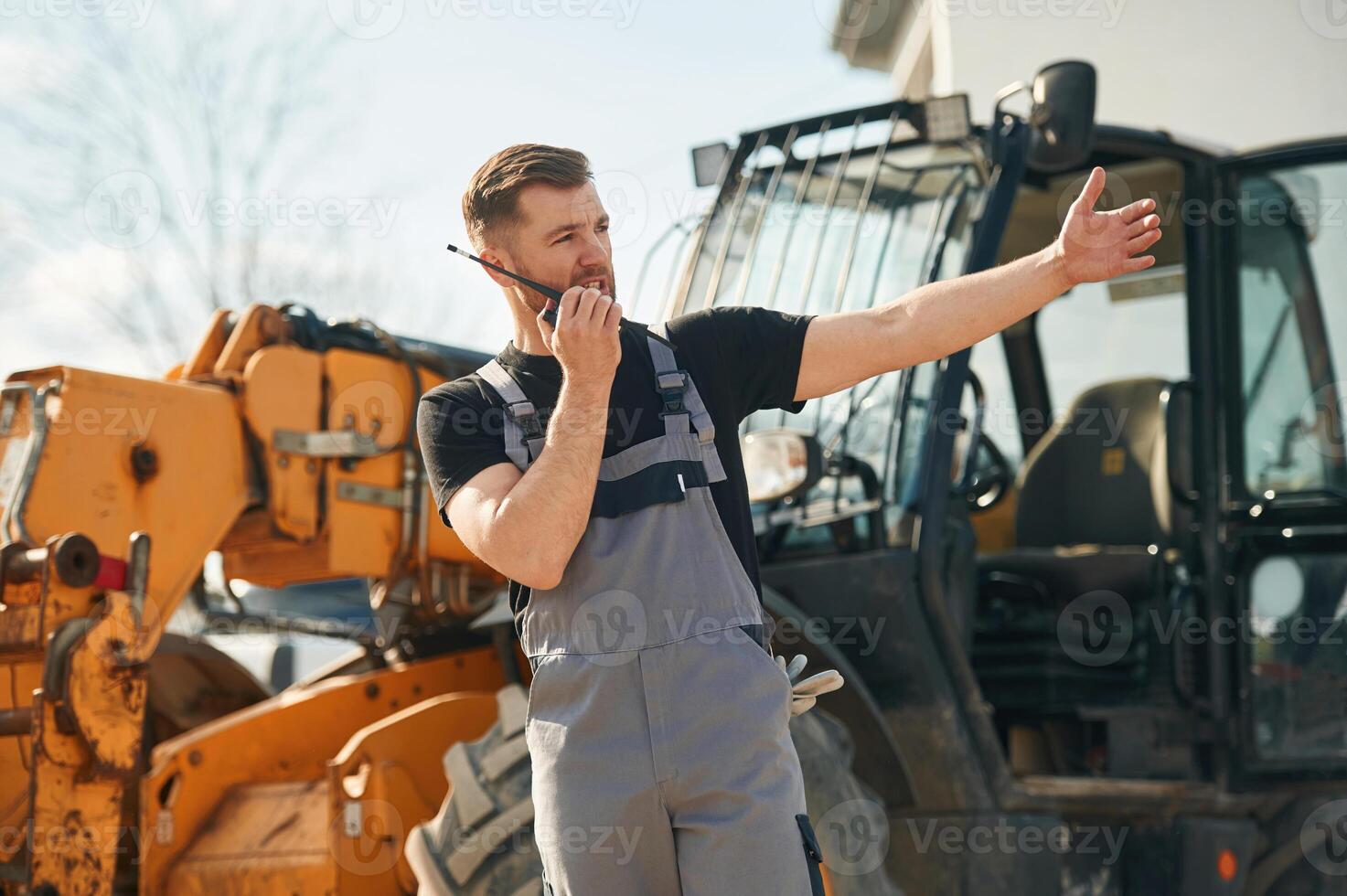 Communication with ,other people by walkie talkie. Man is with tractor. Agricultural worker photo