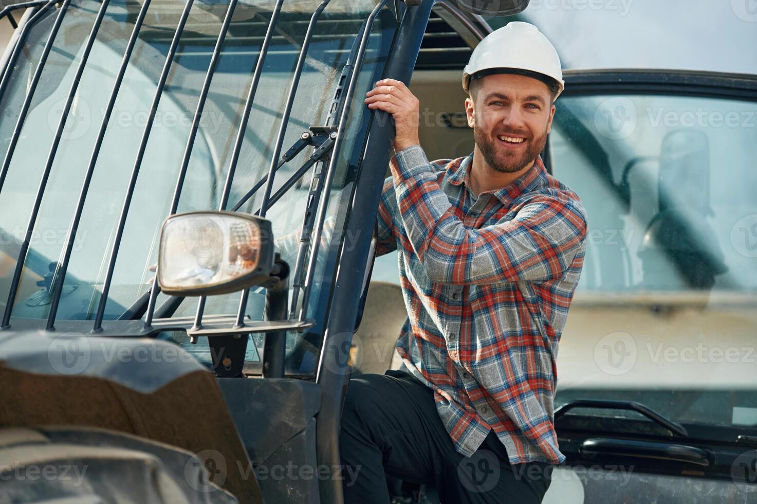 Looking out from the vehicle, smiling. Man is with tractor. Agricultural worker photo