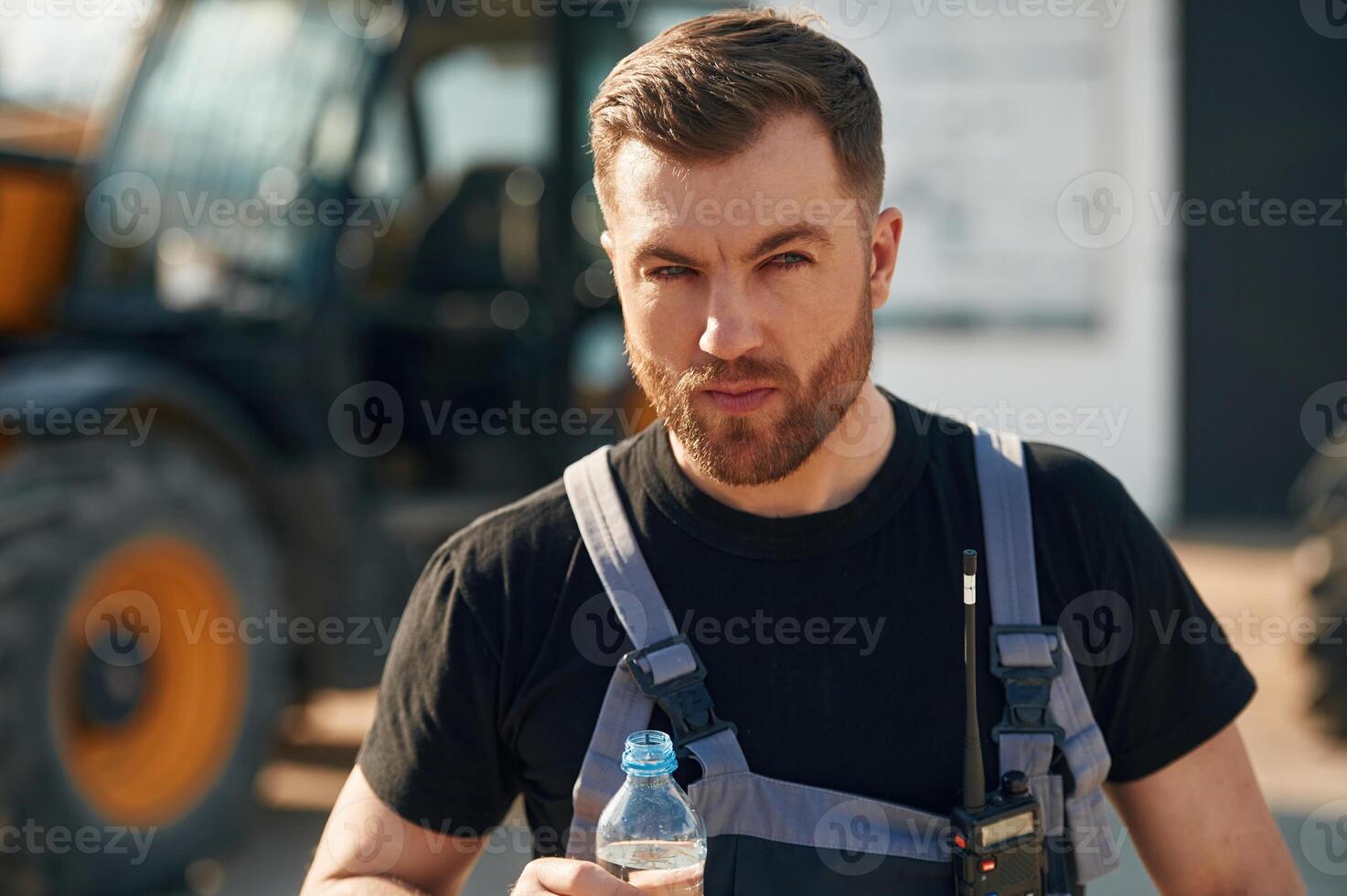 Bottle, of water, drinking, taking a break. Man is with tractor. Agricultural worker photo