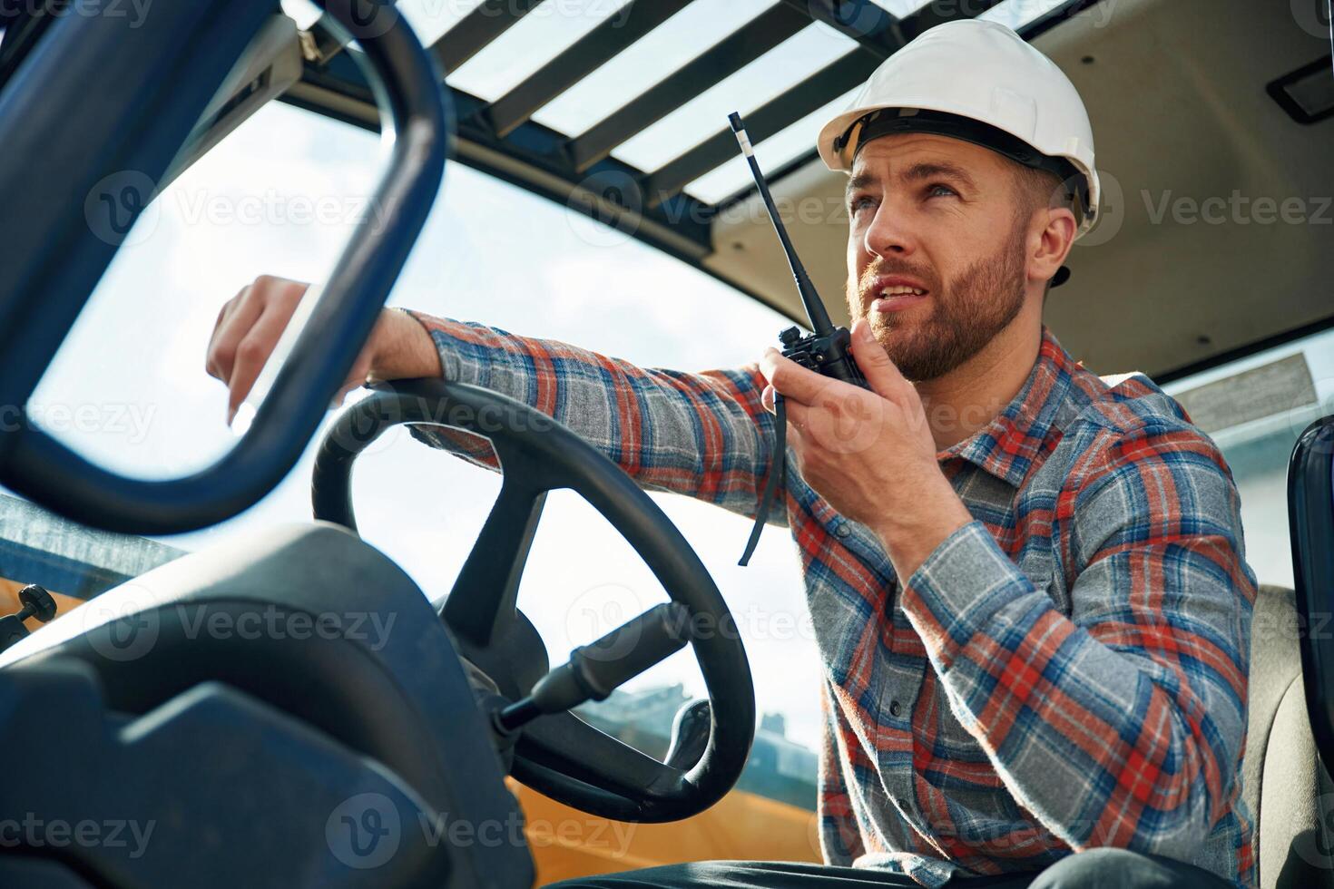 Walkie talkie device,, conversation, orders. Man is with tractor. Agricultural worker photo