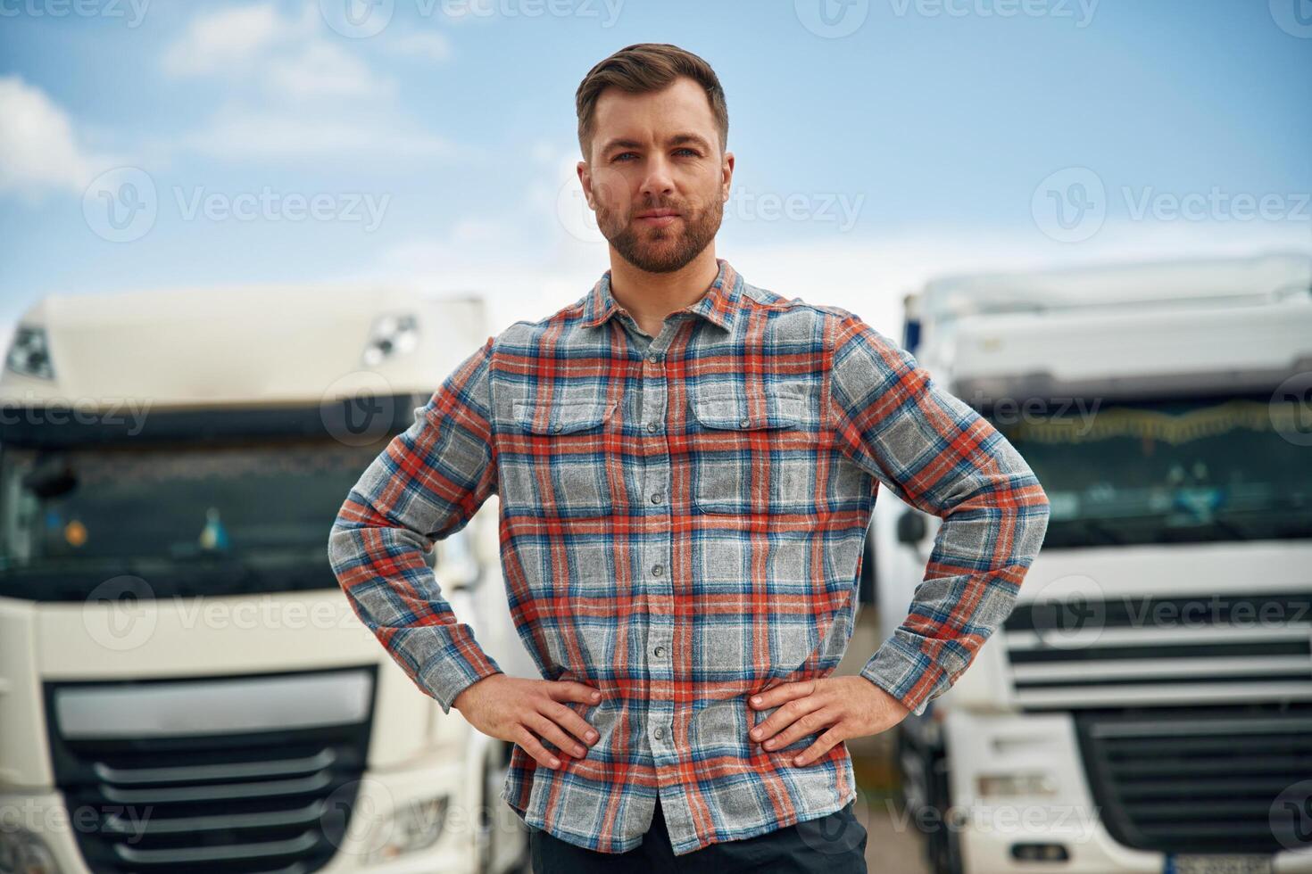 Front, view, standing. Man is standing against trucks outdoors photo