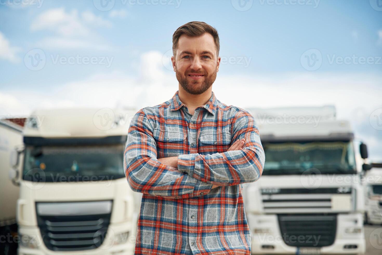 Front view,, standing. Man is standing against trucks outdoors photo