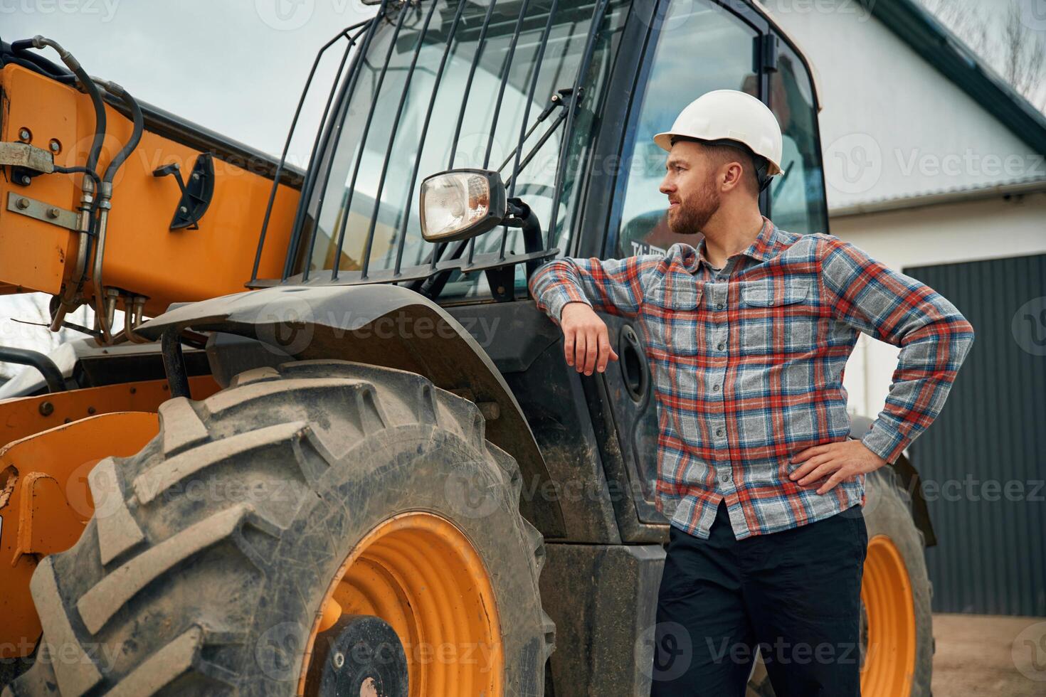 Leaning, on the vehicle. Man is with tractor. Agricultural worker photo