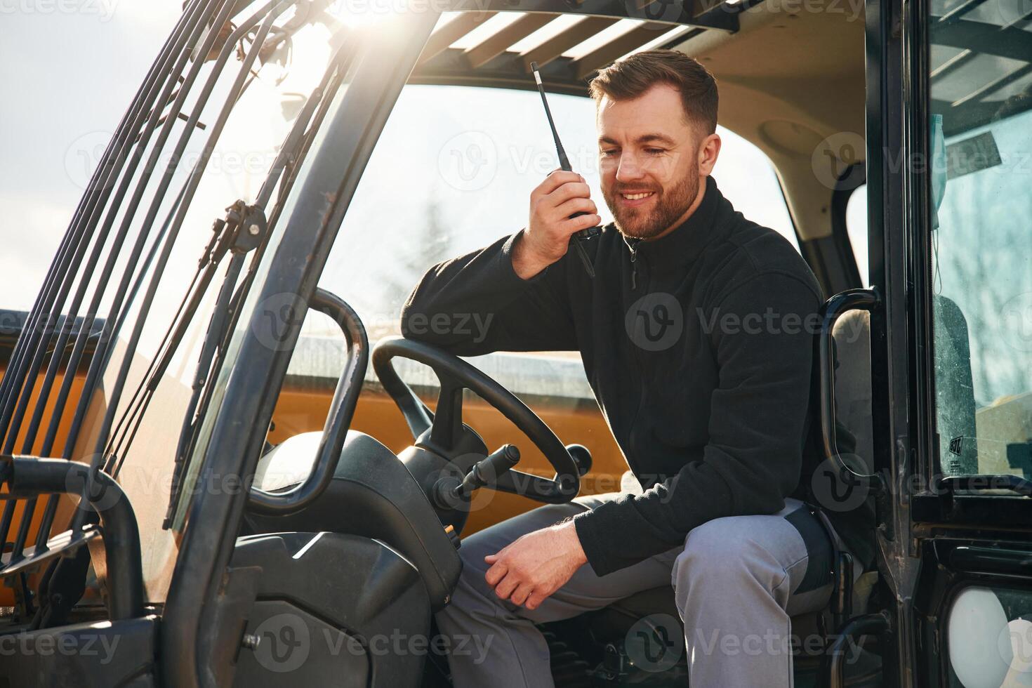 Walkie, talkie device, conversation, orders. Man is with tractor. Agricultural worker photo