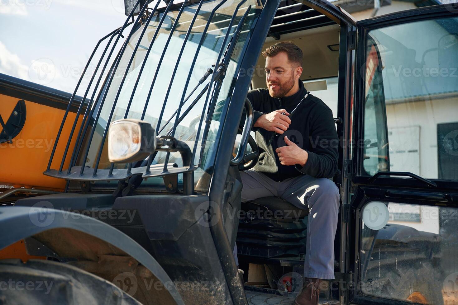 Sitting, in the vehicle. Man is, with tracto..r. Agricultural worker photo
