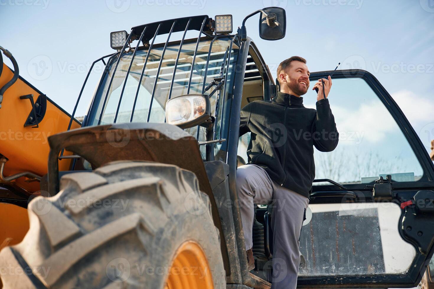 View from below,, using walkie talkie. Man is with tractor. Agricultural worker photo