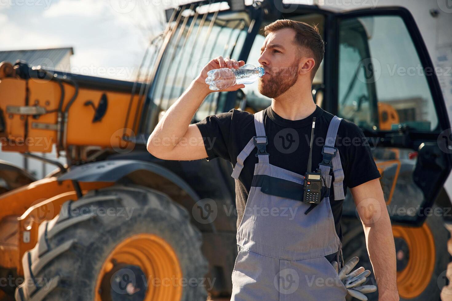 Drinking, water, taking a break, tired. Man is with tractor. Agricultural worker photo